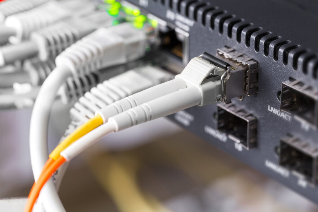 Close-up of high speed fiber network switch and cables in datacenter - article managed wordpress hosting for woocommerce